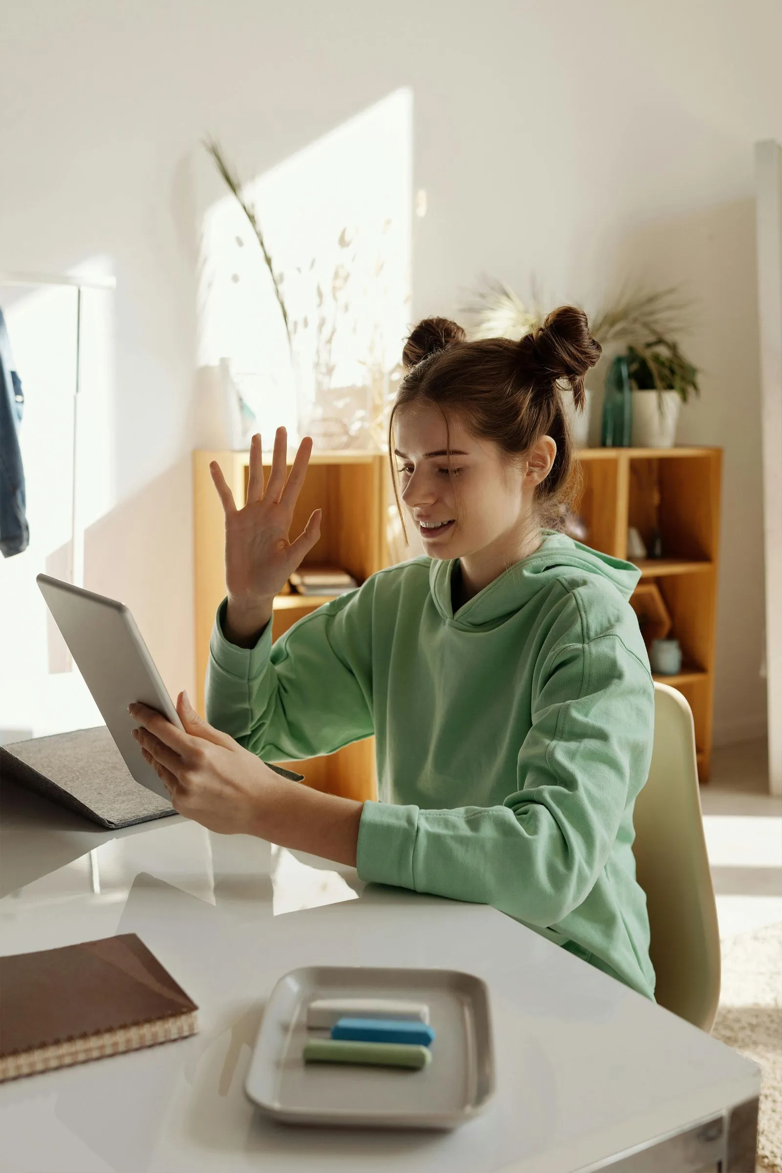 A schoolgirl participates in an online lesson using a tablet