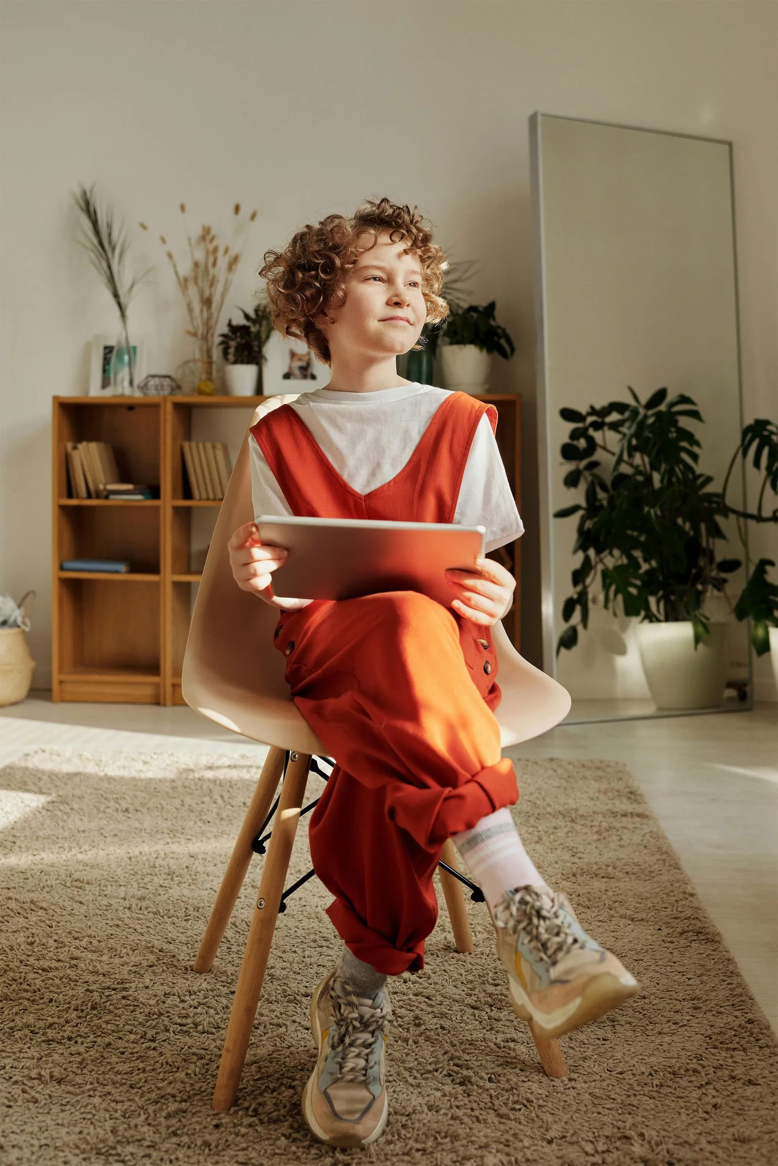 A student wearing a red uniform sits while holding a book in his hands