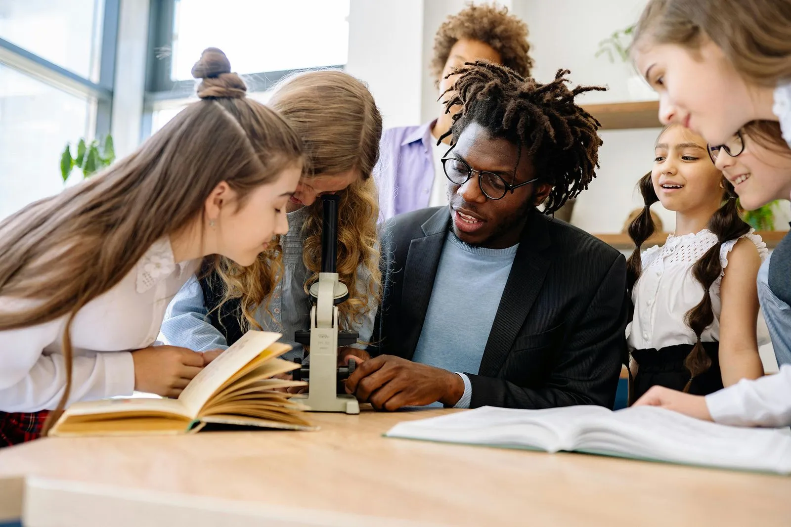 A teacher is showing a microscope to a group of students